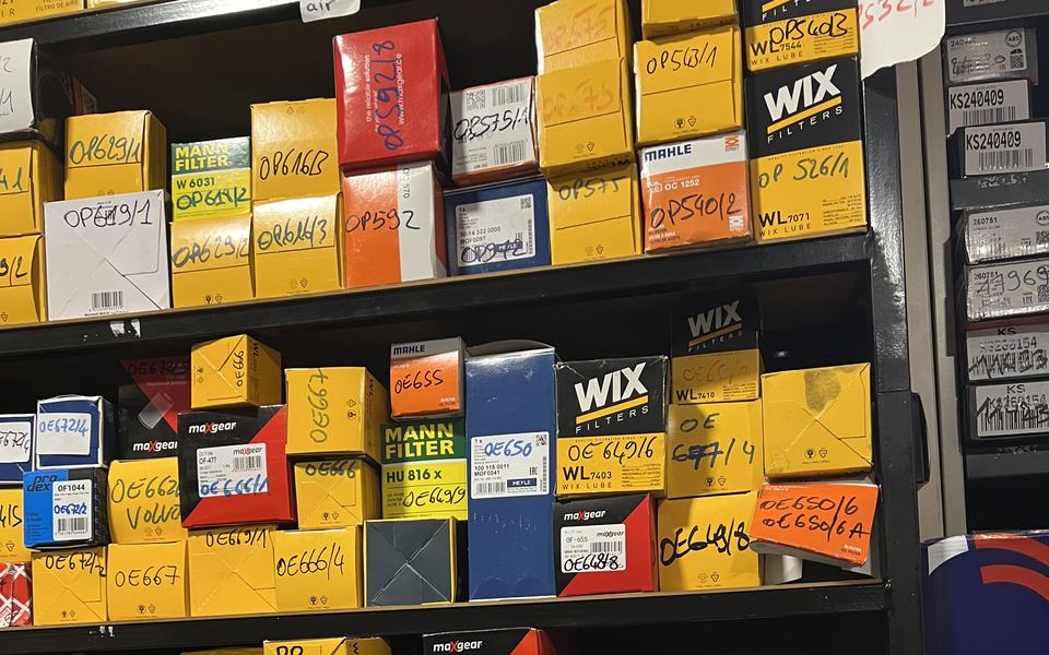 Étagères du magasin : boîtes de filtres, références écrites au marqueur sur chaque carton